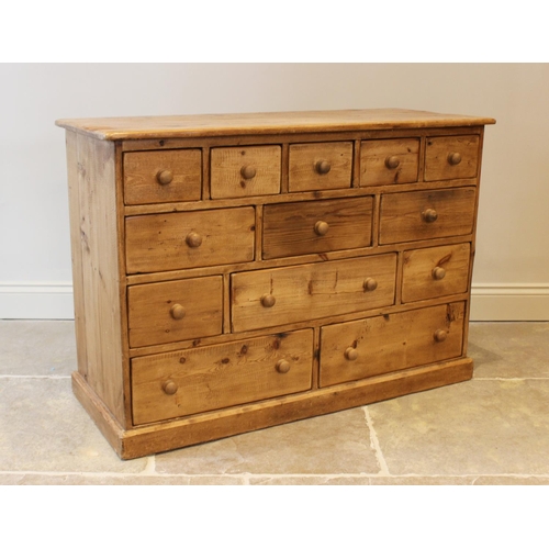 576 - A Victorian style stained pine storage chest, with an arrangement of thirteen assorted drawers upon ... 