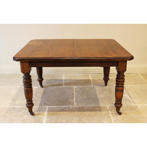 618 - An Edwardian oak extending dining table with canted corners and raised on turned baluster legs, 73cm... 