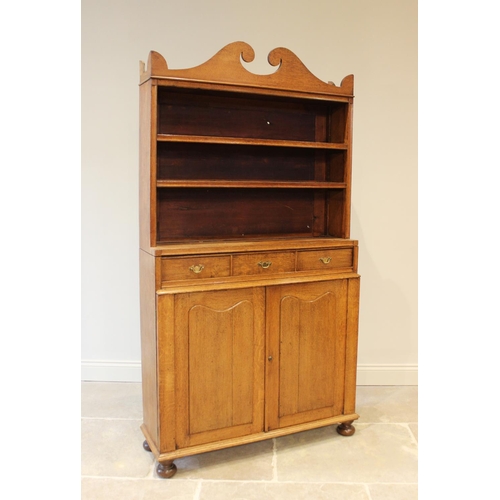 632 - An early 20th century honey oak library open bookcase, the broken pediment top over two open shelves... 