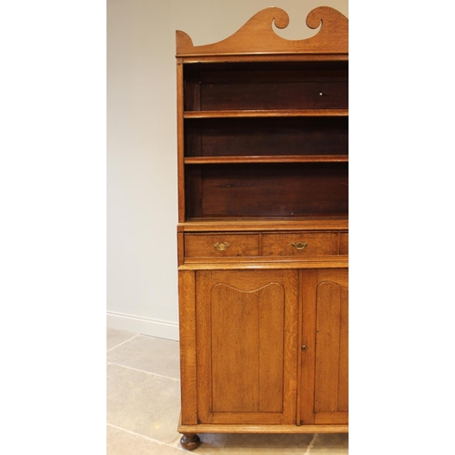 632 - An early 20th century honey oak library open bookcase, the broken pediment top over two open shelves... 