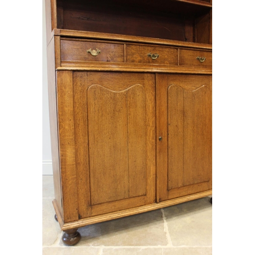 632 - An early 20th century honey oak library open bookcase, the broken pediment top over two open shelves... 