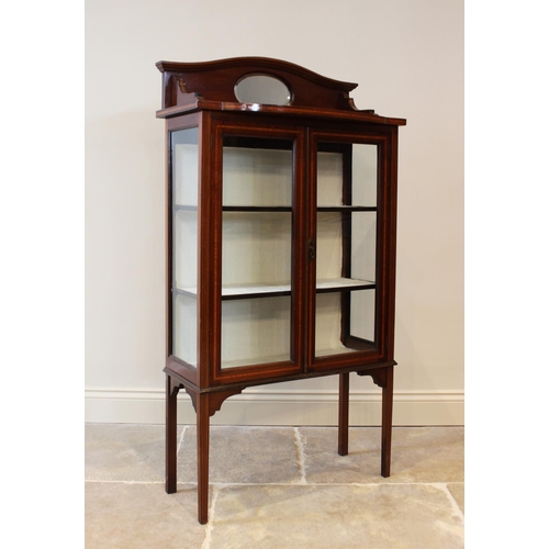 635 - An Edwardian mahogany display cabinet, the serpentine raised back centred with an oval mirror, above... 