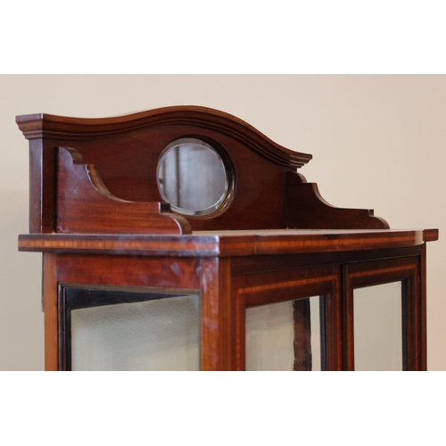 635 - An Edwardian mahogany display cabinet, the serpentine raised back centred with an oval mirror, above... 