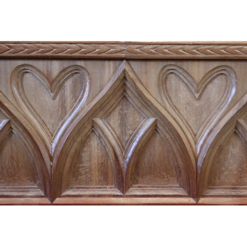 646 - A carved oak Gothic revival headboard, 20th century, 151cm wide, along with a matched bedside table ... 