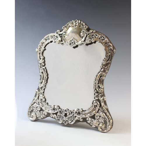 79 - An Art Nouveau silver mounted mirror by Henry Matthews, Birmingham 1902, the shaped border with embo... 