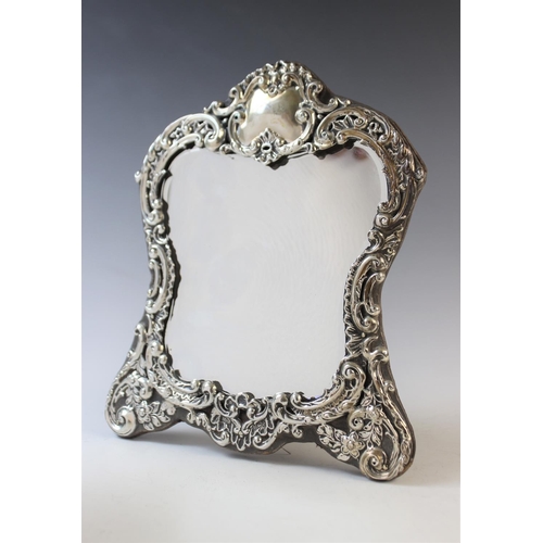 79 - An Art Nouveau silver mounted mirror by Henry Matthews, Birmingham 1902, the shaped border with embo... 