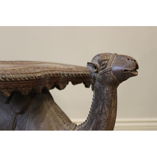 579 - An Anglo-Indian camel form occasional table, 19th century, the kidney shaped table top carved with a... 