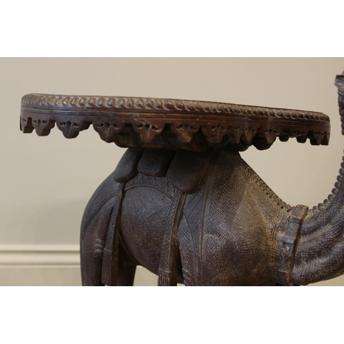 579 - An Anglo-Indian camel form occasional table, 19th century, the kidney shaped table top carved with a... 