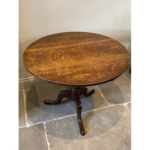 559 - A George III oak tripod table, the circular three plank top on a ring turned baluster column upon th... 