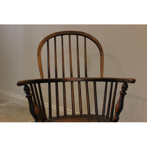 758 - An early 19th century elm and ash hoop back Windsor chair, the shaped elm seat raised upon turned le... 