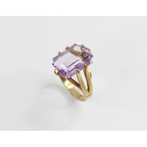 145 - An amethyst set 9ct gold dress ring, the central rectangular mixed cut stone with canted corners, (m... 