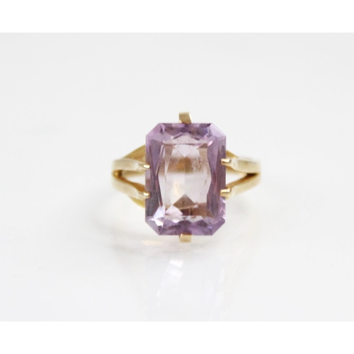 145 - An amethyst set 9ct gold dress ring, the central rectangular mixed cut stone with canted corners, (m... 