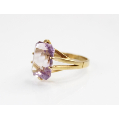 145 - An amethyst set 9ct gold dress ring, the central rectangular mixed cut stone with canted corners, (m... 