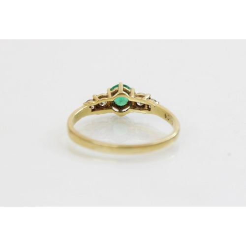 152 - An emerald and diamond 18ct gold ring, the central round mixed cut emerald (measuring 5mm diameter),... 