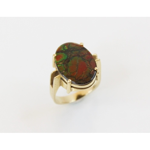 154 - An ammolite triplet ring, the central oval ammolite panel (measuring 17mm x 12mm), claw set to pierc... 