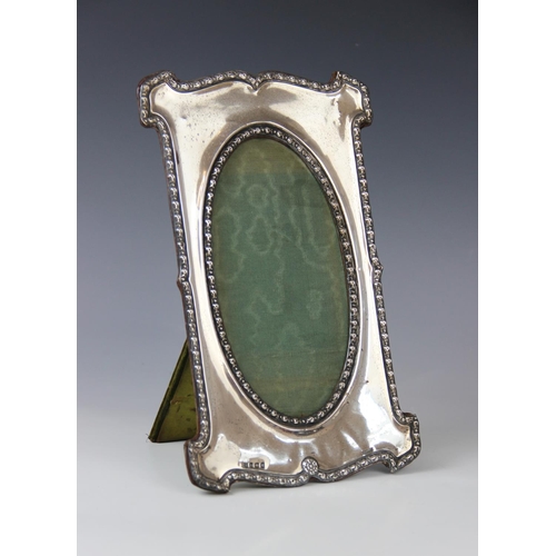 22 - An Edwardian silver mounted photograph frame by Charles S Green & Co Ltd, Birmingham 1906, of shaped... 
