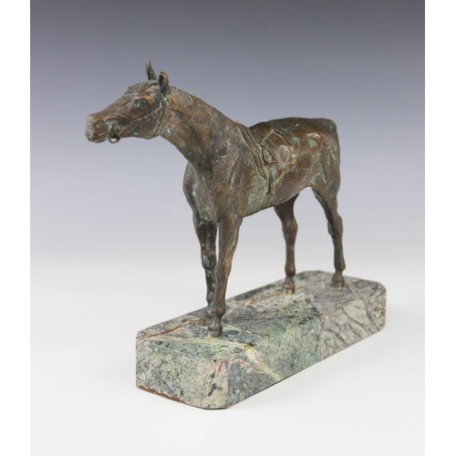 340 - A bronze patinated sculpture of a racehorse, modelled standing saddled, set to a green marble plinth... 