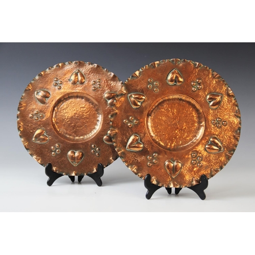 351 - A pair of Arts & Crafts copper chargers, early 20th century, each of circular form with shaped rim, ... 