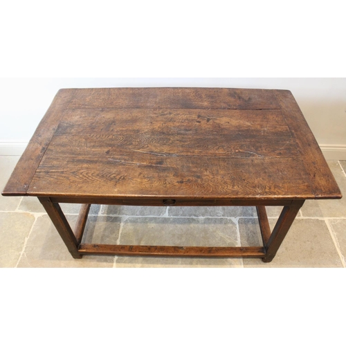 595 - An early 18th century oak kitchen table, the cleated plank top raised upon chamfered legs of square,... 