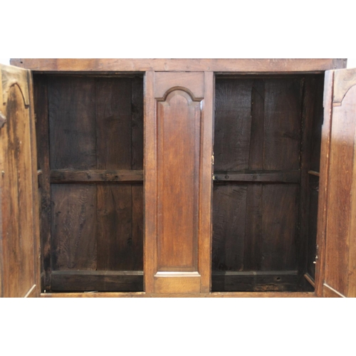 600 - An 18th century oak livery cupboard, the moulded cornice above a pair of fielded panelled cupboard d... 