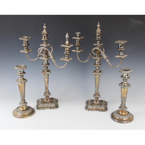 69 - A pair of early 20th century silver plated three-branch candelabras, each on shaped square bases and... 