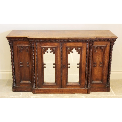 690 - A late 19th century oak Gothic influence breakfront credenza/sideboard, the moulded top above a carv... 