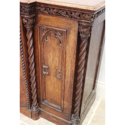 690 - A late 19th century oak Gothic influence breakfront credenza/sideboard, the moulded top above a carv... 