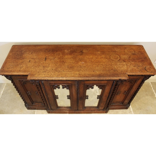 690 - A late 19th century oak Gothic influence breakfront credenza/sideboard, the moulded top above a carv... 