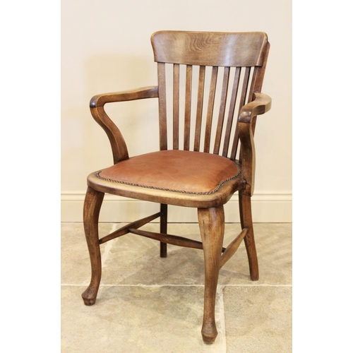 719 - An early 20th century stained beech wood desk chair, the lath back above a shaped padded seat applie... 