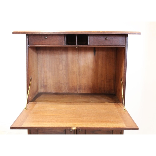 722 - An early 20th century Arts and Crafts oak secretaire abattant, of tapering form, the overhanging cor... 