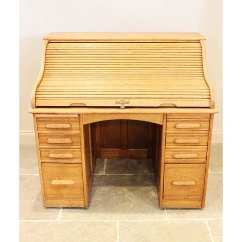 726 - An Edwardian oak roll top desk, the central knee hole flanked by two banks of four drawers below a f... 