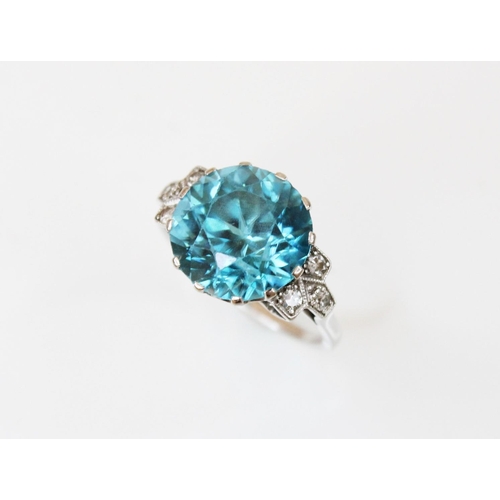 143 - An Art Deco blue zircon and diamond ring, the central round mixed cut zircon (measuring 12mm diamete... 