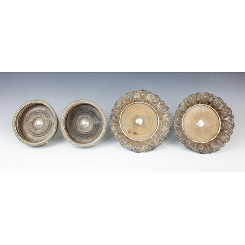 67 - A pair of white metal mid-19th century bottle coasters, each with turned circular mahogany bases wit... 