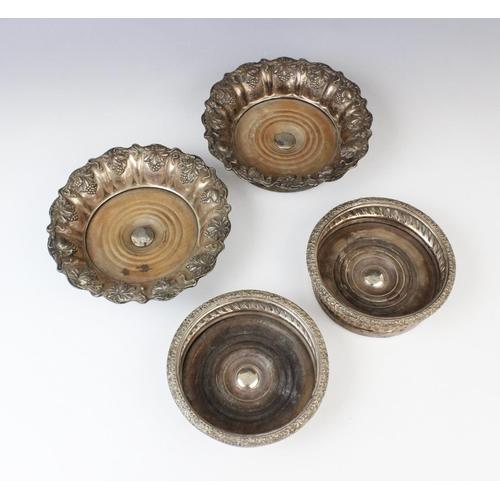 67 - A pair of white metal mid-19th century bottle coasters, each with turned circular mahogany bases wit... 