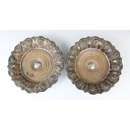 67 - A pair of white metal mid-19th century bottle coasters, each with turned circular mahogany bases wit... 