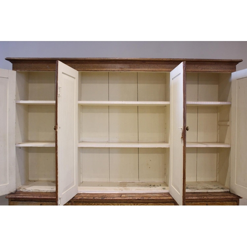 705 - A Victorian scumbled pine housekeepers cupboard, the moulded cornice above four invert panelled cupb... 