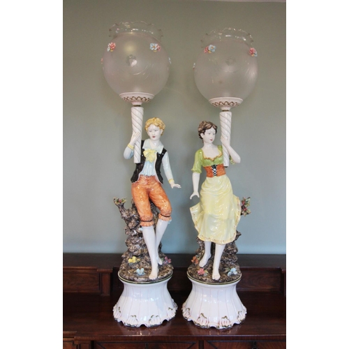 211 - A pair of continental porcelain floor standing figural lamps, mid to late 20th century, modelled as ... 