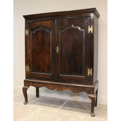 605 - A mid 18th century and later oak cabinet on stand, the moulded cornice above two fielded panel doors... 