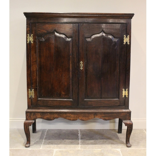 605 - A mid 18th century and later oak cabinet on stand, the moulded cornice above two fielded panel doors... 