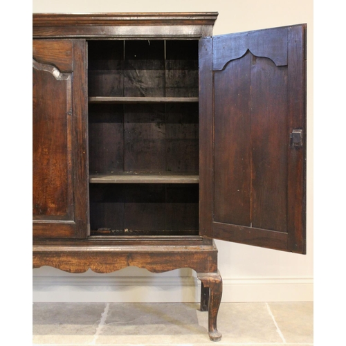 605 - A mid 18th century and later oak cabinet on stand, the moulded cornice above two fielded panel doors... 