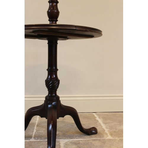 622 - A George III mahogany two tier dumb waiter, the two graduated circular trays raised upon baluster an... 