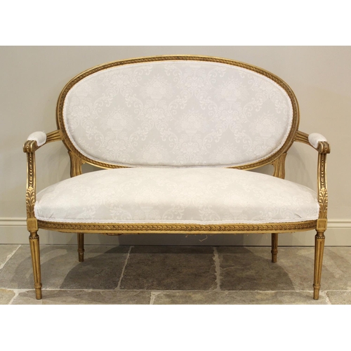 646 - A Louis XVI style giltwood settee, early 20th century, in classical white foliate pattern fabric, th... 