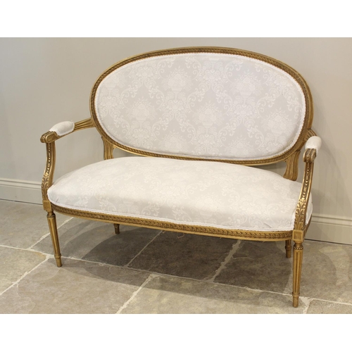 646 - A Louis XVI style giltwood settee, early 20th century, in classical white foliate pattern fabric, th... 