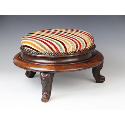 650 - A Victorian mahogany circular foot stool, in striped fabric, raised upon three squat cabriole legs t... 