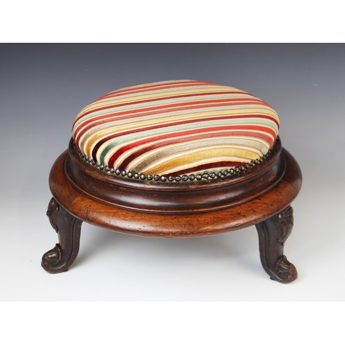 650 - A Victorian mahogany circular foot stool, in striped fabric, raised upon three squat cabriole legs t... 