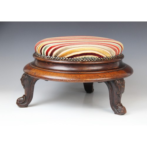 650 - A Victorian mahogany circular foot stool, in striped fabric, raised upon three squat cabriole legs t... 