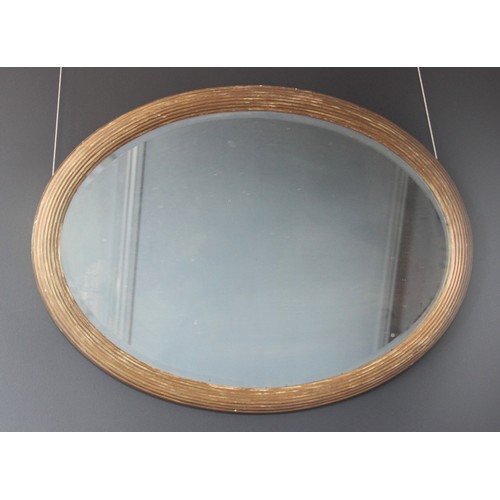 574 - A 19th century gilt wood oval wall mirror, the bevelled mirrored plate within a reeded frame, 84cm H... 