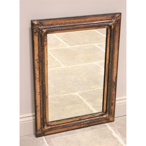 567 - An early 20th century Arts and Crafts copper wall mirror, the rectangular mirrored plate within a ha... 