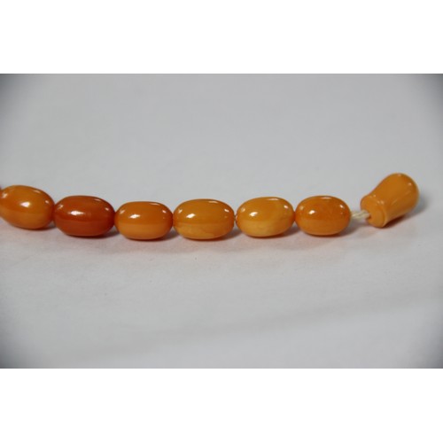 99 - A butterscotch amber bead necklace, comprising fifty-one graduated plain polished oval beads measuri... 