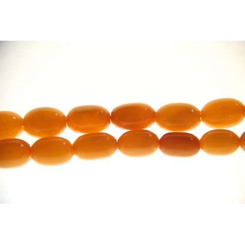 99 - A butterscotch amber bead necklace, comprising fifty-one graduated plain polished oval beads measuri... 